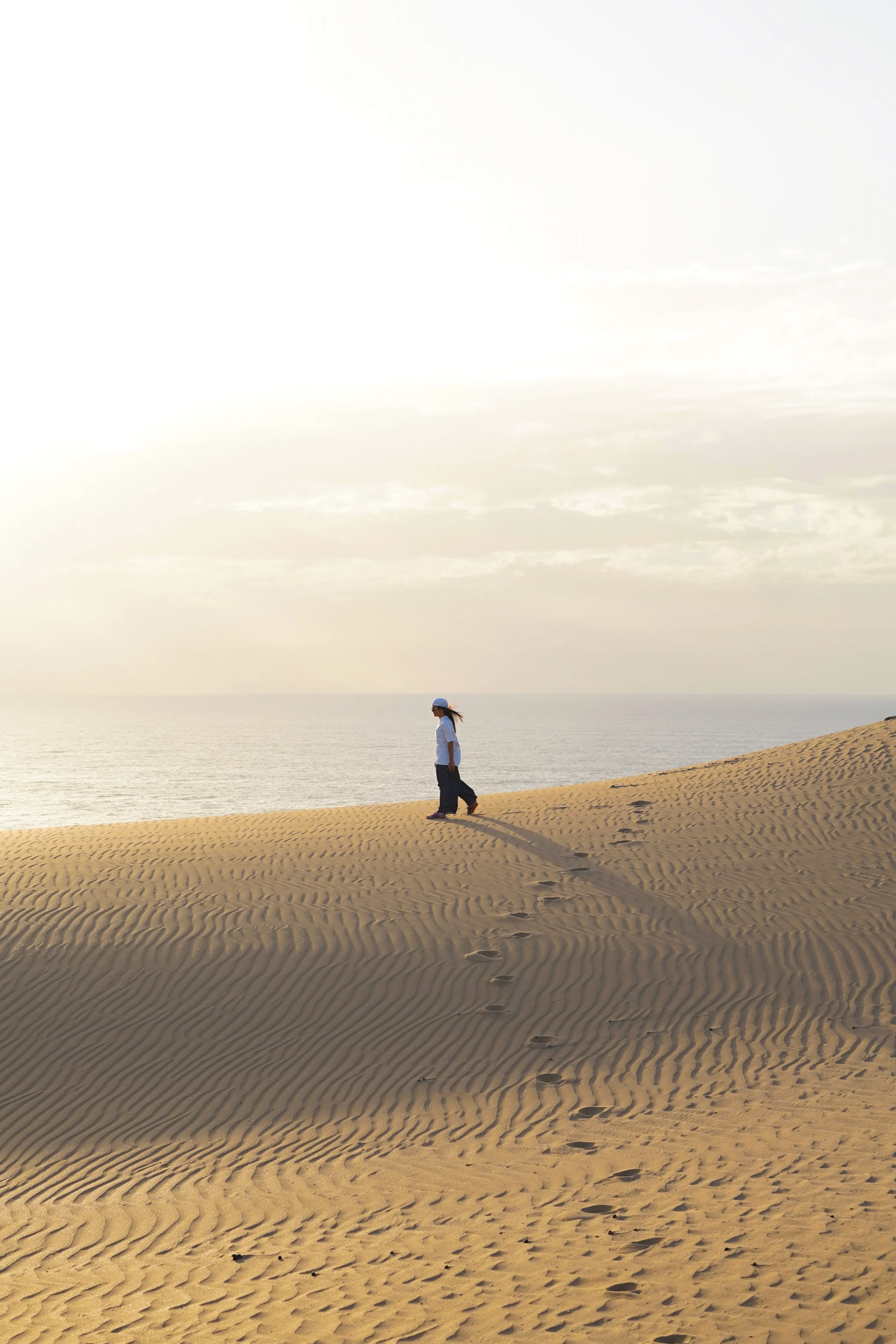 Surfeur de dos marchant dans les dunes de Taghazout